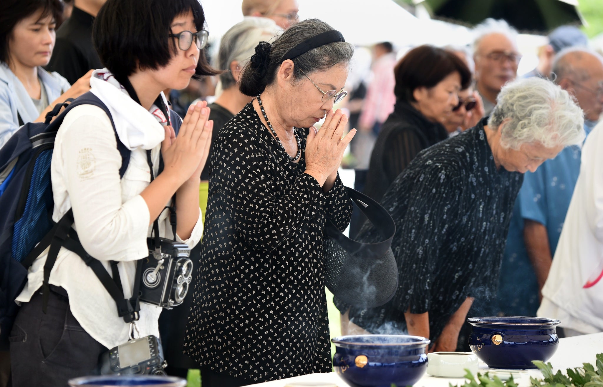 People put their hands together to pray at an altar at the Peace Memorial Park in Itoman