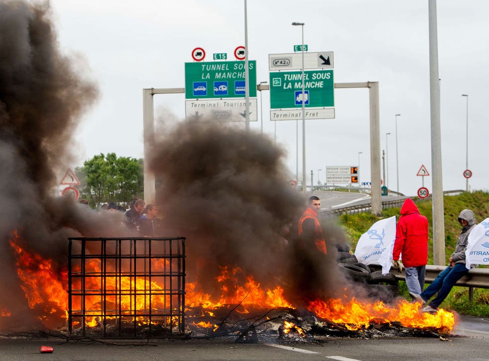 Striking employees of the French company My Ferry Link, a cross-channel ferry service, stand in front of tyres set on fire as they block the access to the Channel Tunnel in Calais, northern France 