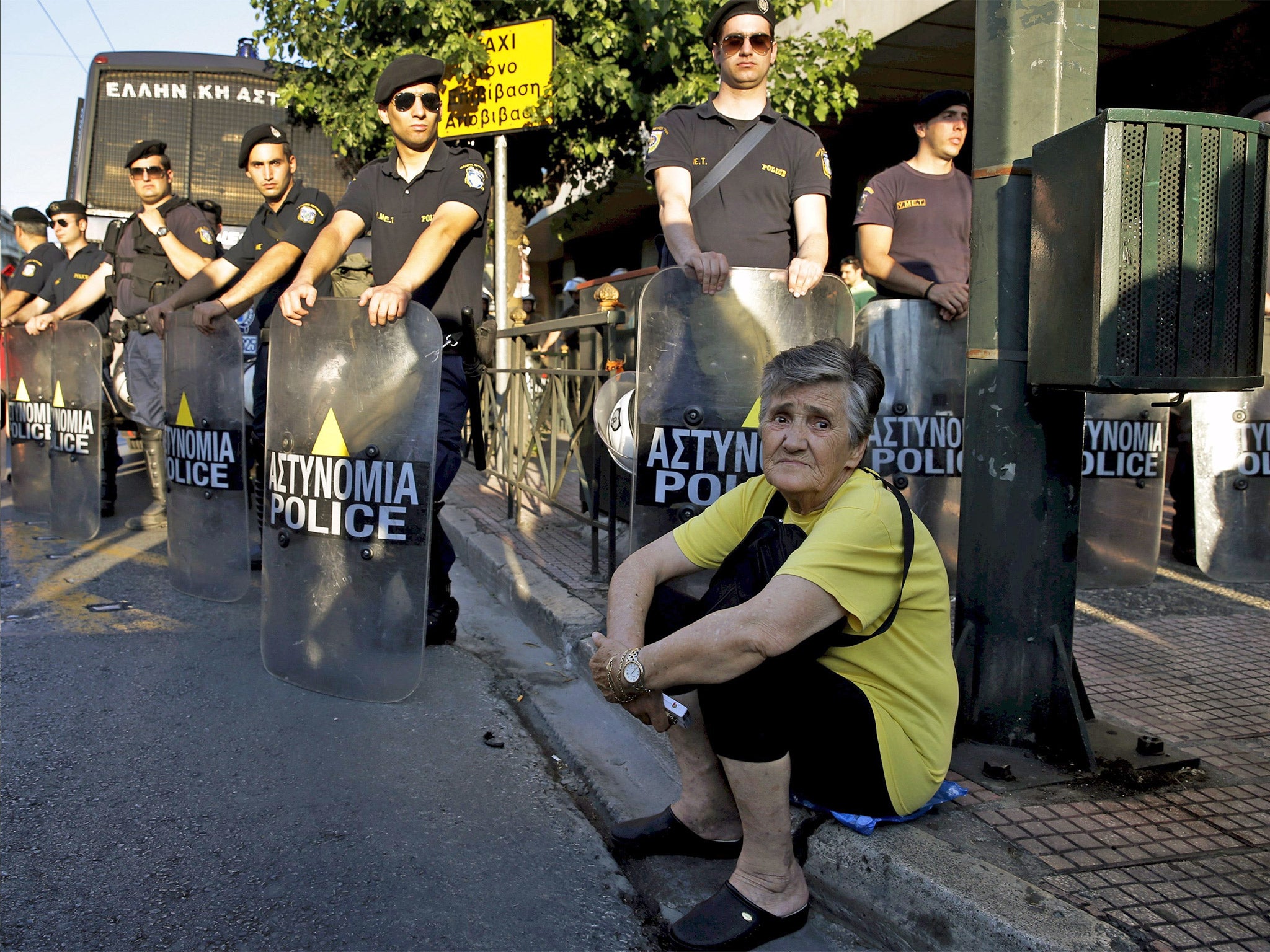 A pensioner rests by riot policemen blocking the street to the PM’s office