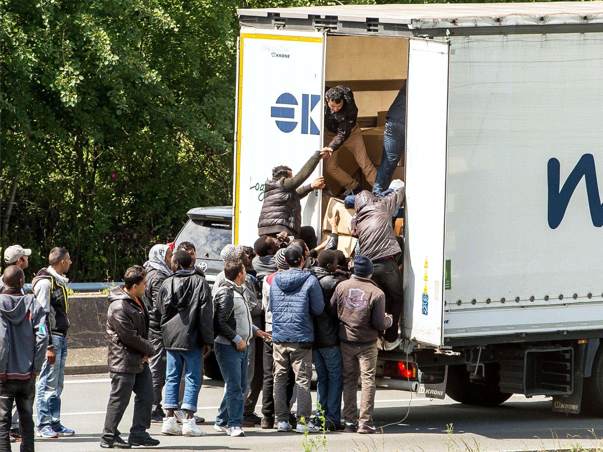 Migrants climb in the back of a lorry on the A16 highway leading to the Eurotunnel in Calais, June 2015