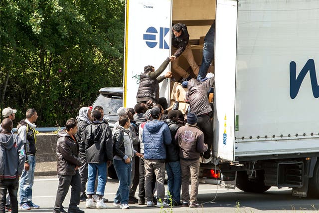 Migrants climbing into the back of a lorry on the A16 highway in northern France leading to the Channel Tunnel 