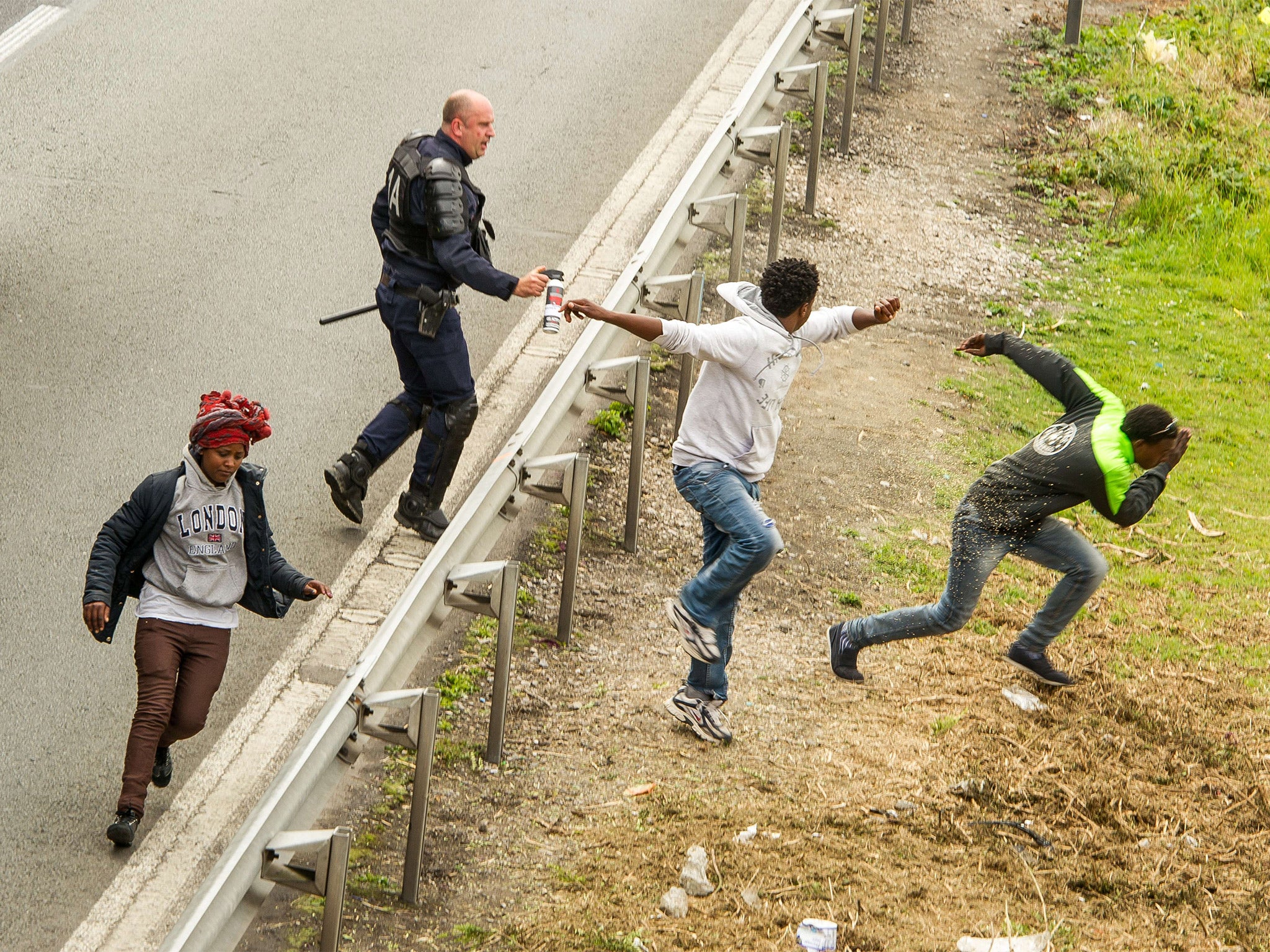 A police officer sprays tear gas at migrants on the A16 highway in Calais (Getty)