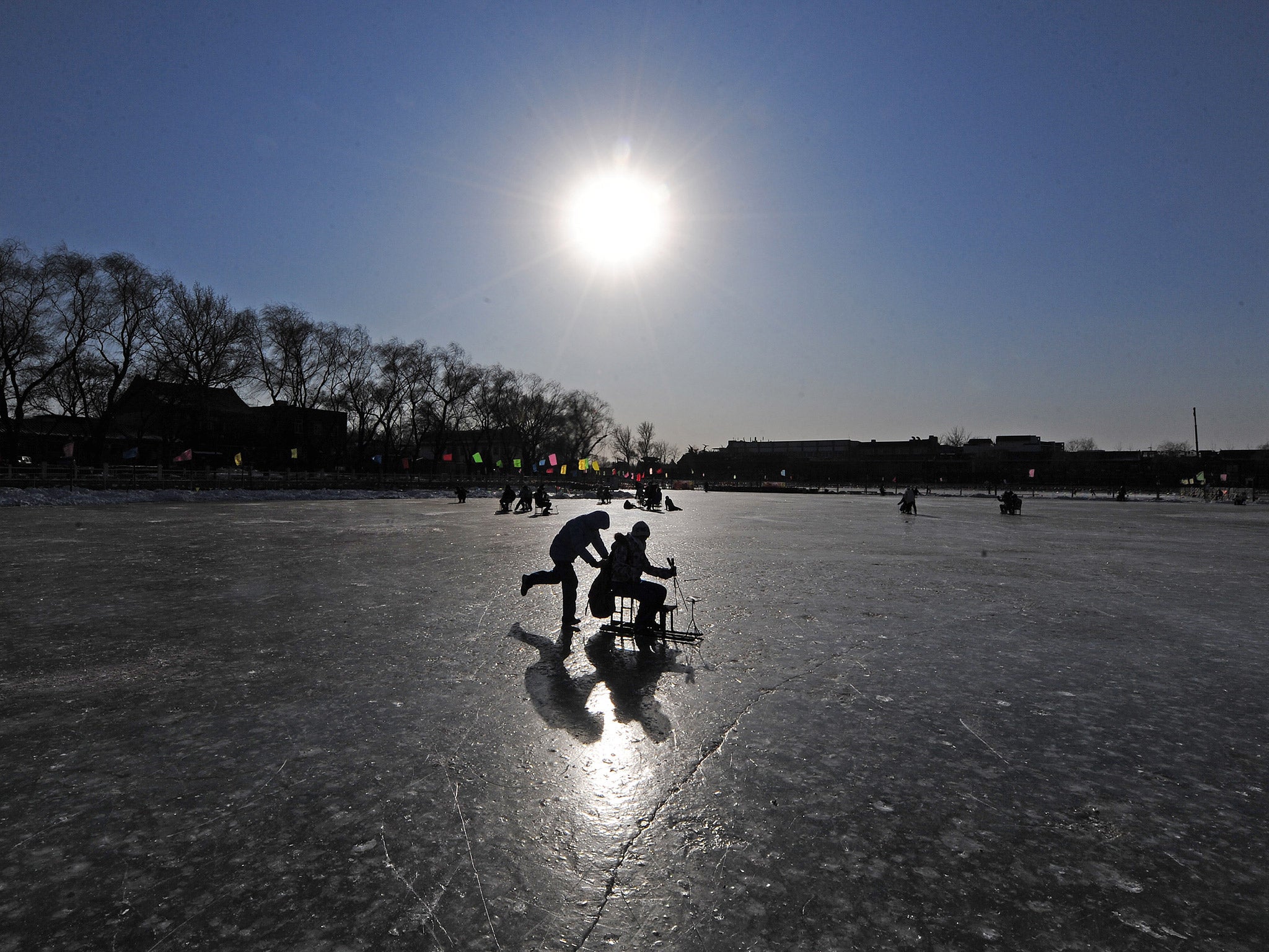 People play on a frozen lake at in central Beijing. File photo