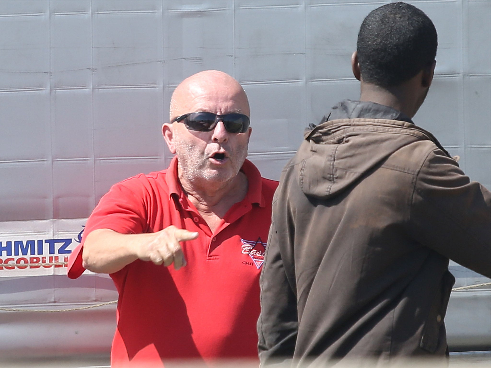 A lorry driver shouts at migrants after they try and board a UK bound lorry on the main road into Calais ferry port