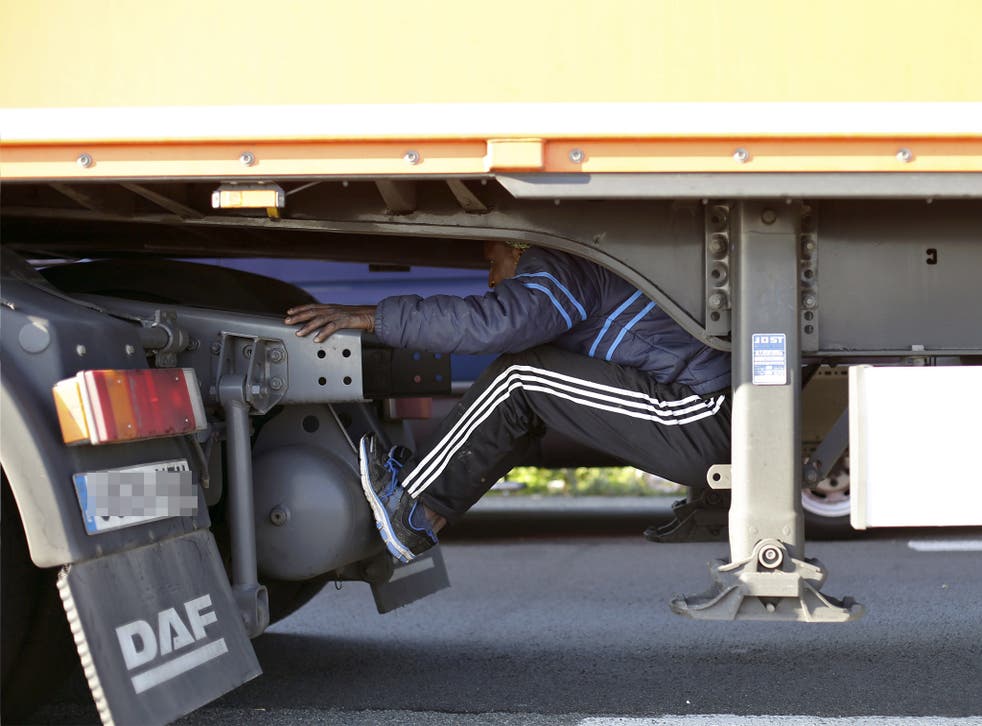 A migrant sits under the trailer of a lorry