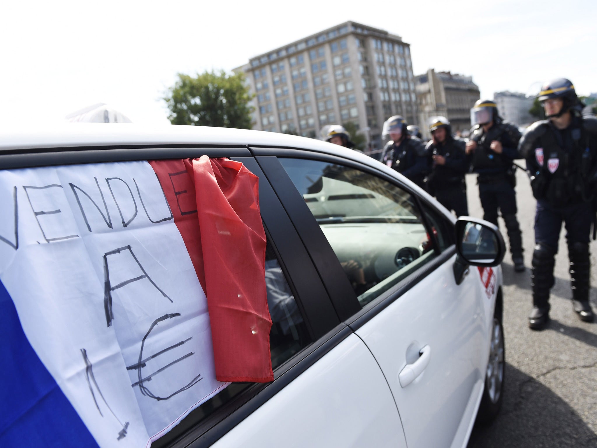 Riot police stand guard in central Paris as taxi drivers protest against Uber