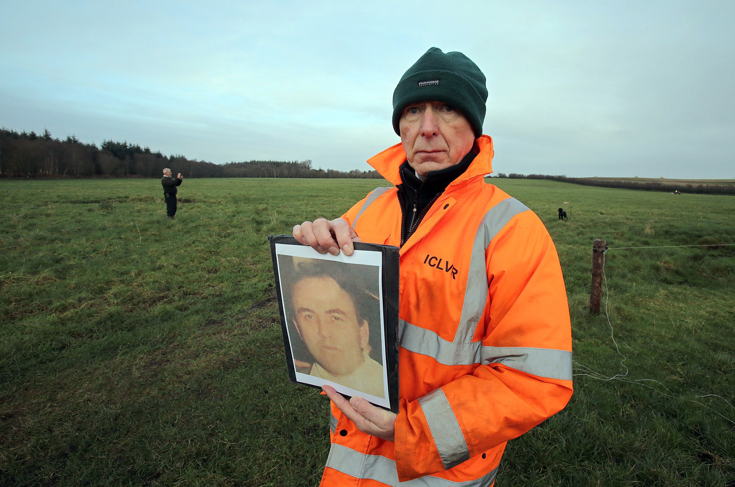 Pictured in December 2014, Geoff Knupfer, the lead forensic scientist and investigator for the Independent Commission for the Location of Victims Remains (ICLVR), holds a picture of Joe Lynskey at the site where his remains are believed to have been found