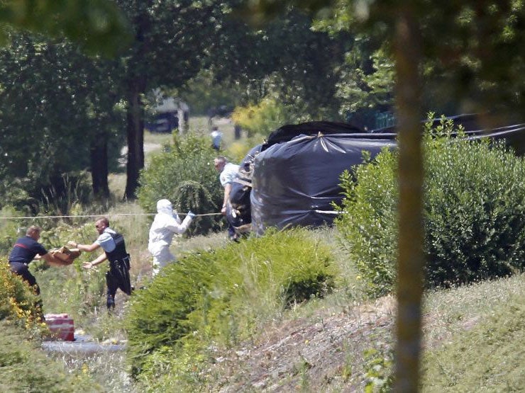 Forensic investigators and gendarmes next to the fence where the head was found in Saint-Quentin-Fallavier