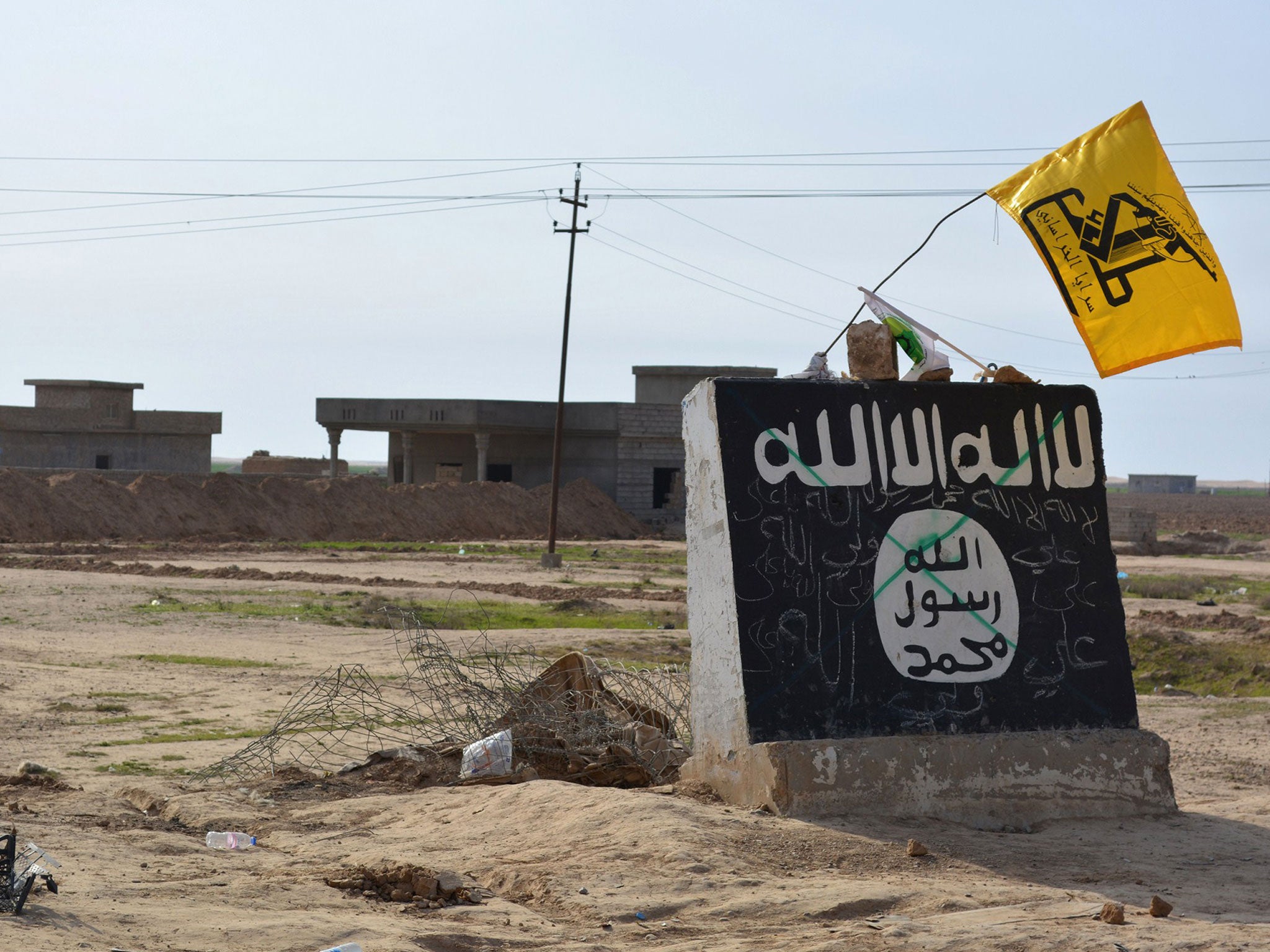 A flag of the Shiite Hezbollah militant group flies over an Isis mural