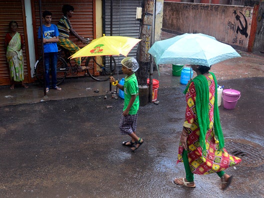 People in Kolkata shelter from the rain as the monsoon arrives