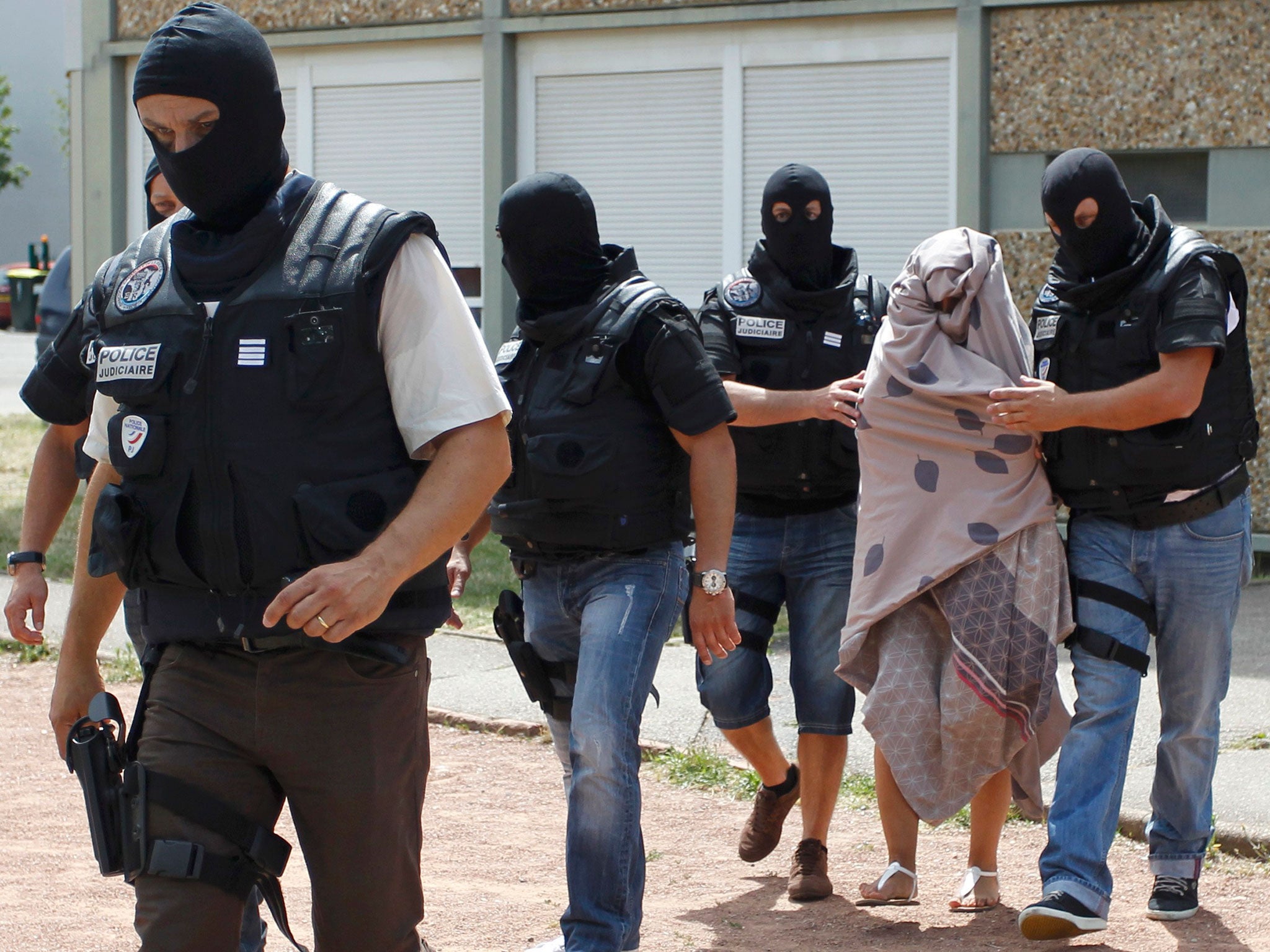 French special Police forces escort a woman from a residential building during a raid in Saint-Priest, near Lyon