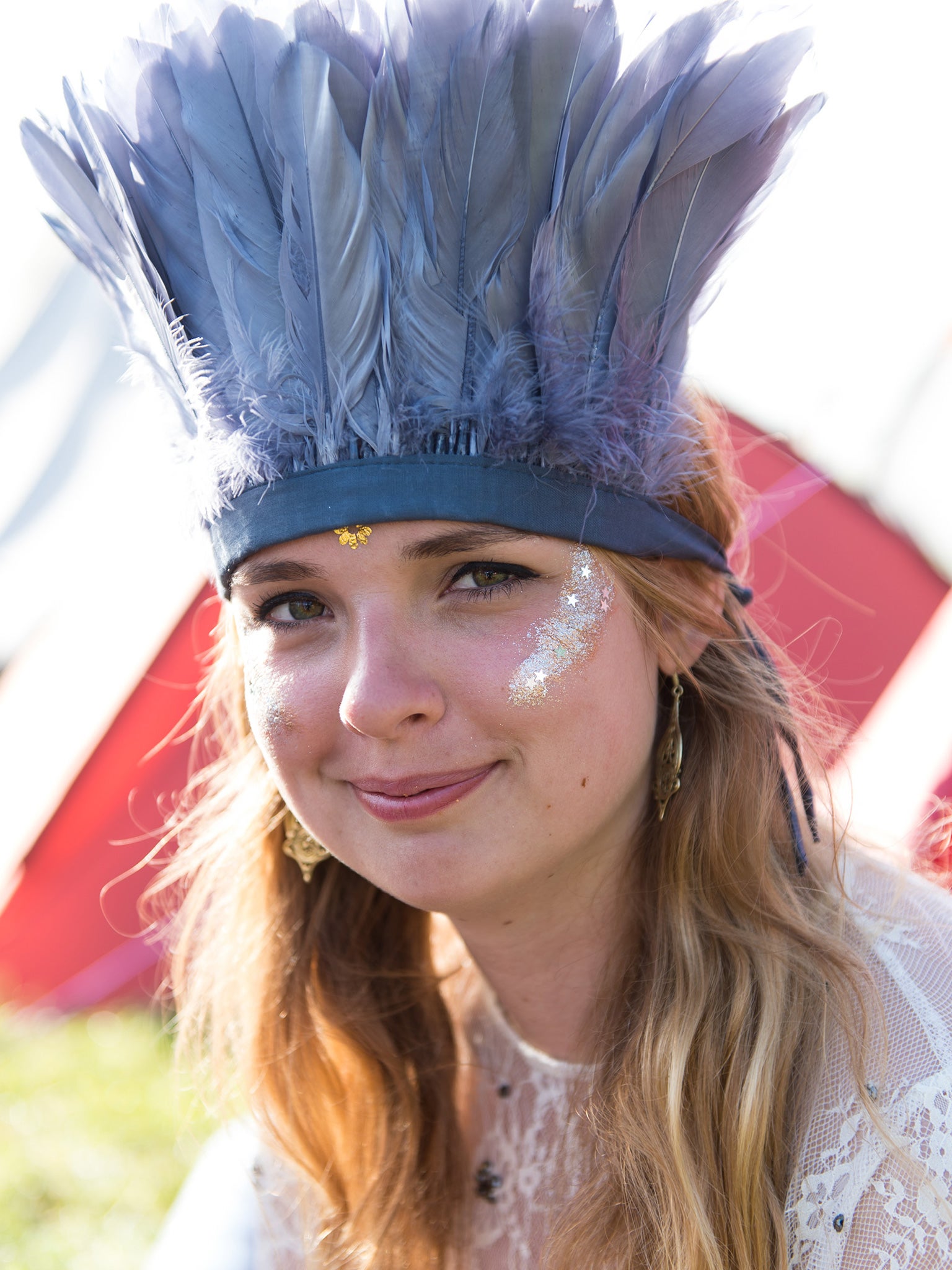 A festival-goer sports a feathered headdress at Glastonbury