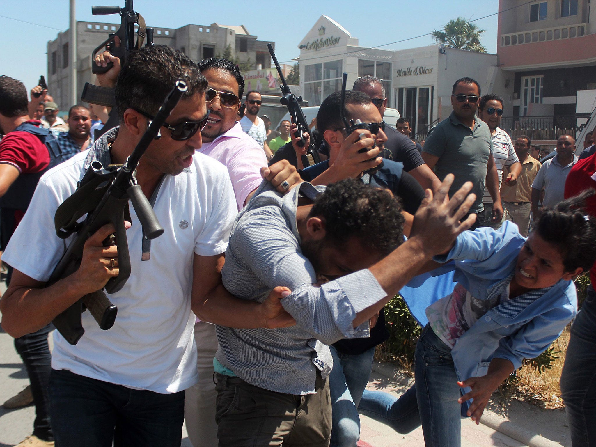 Members of the Tunisian security forces escort a man through a street in al-Sousse