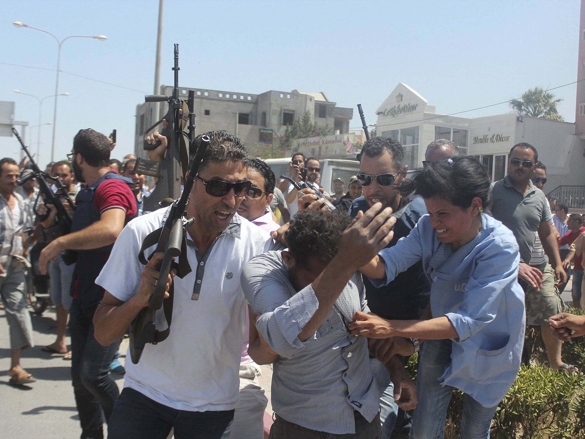 Police officers control the crowd while surrounding a man suspected to be involved in opening fire