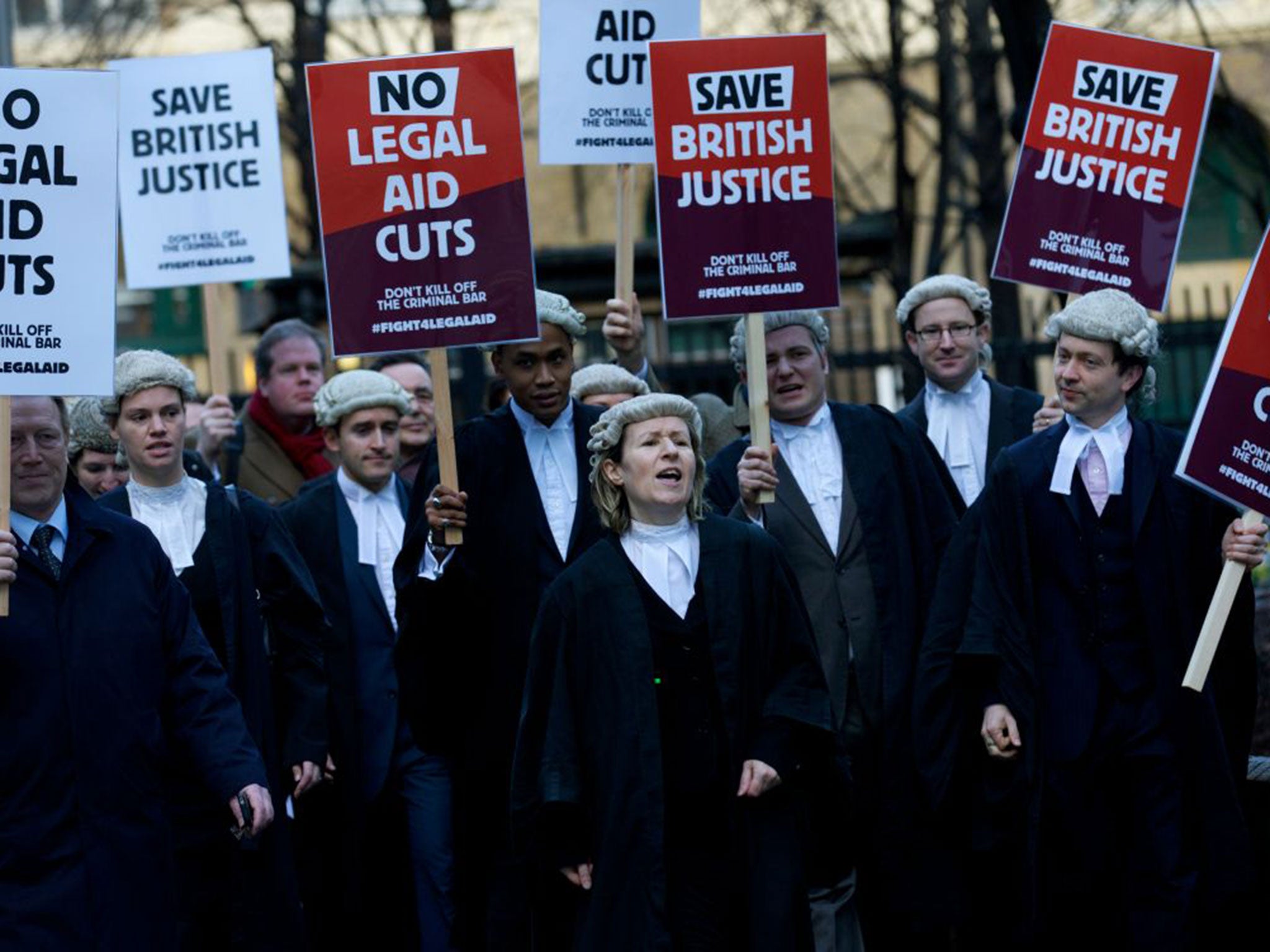 British legal professionals hold placards during a protest against cuts to the legal aid budget during a protest outside Southwark Crown Court in London