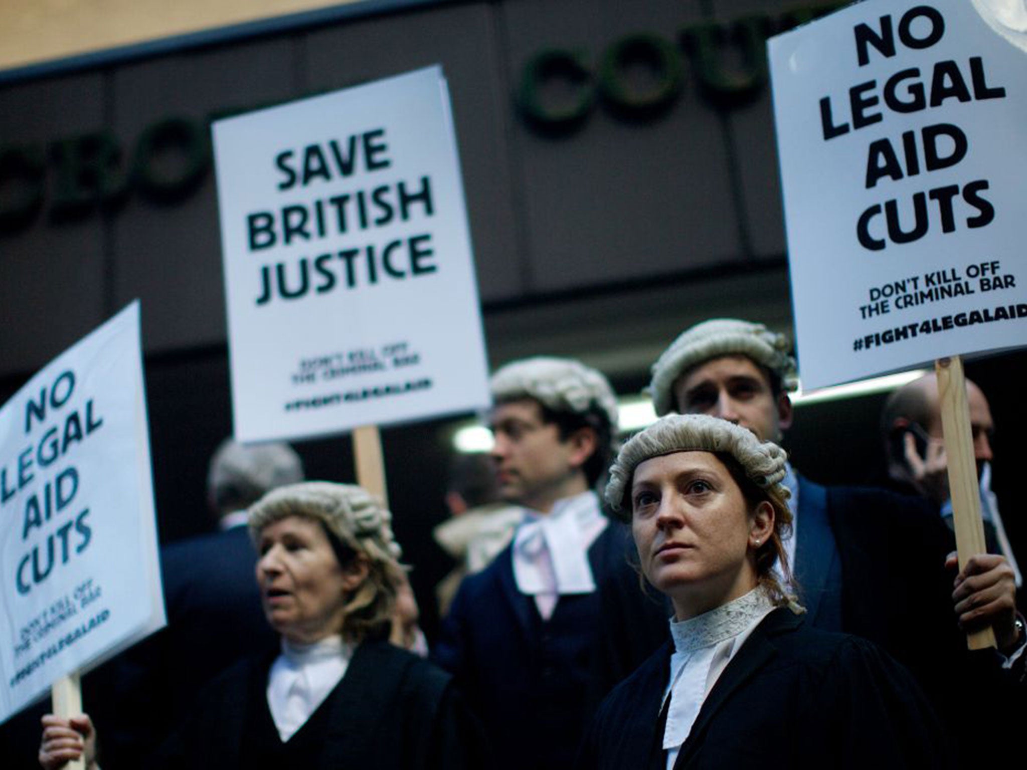 British legal professionals hold placards during a protest against cuts to the legal aid budget during a protest outside Southwark Crown Court in London