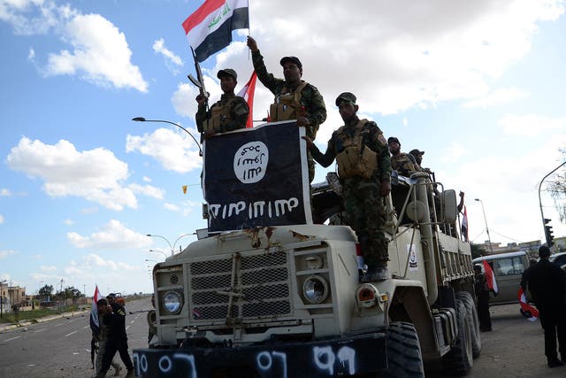 Shiite fighters from the Popular Mobilisation units celebrate on a truck with a national flag and a board they seized from the Islamic State