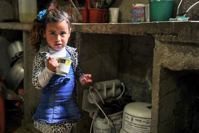 A child with a domestic water filter. After the ceasefire children returned to their homes but the rust-filled water from the taps was no longer safe to drink
