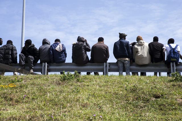 Tense wait: Migrants by the Calais access road to the Channel Tunnel seek a vehicle that they can hide in and which will take them across to Britain 