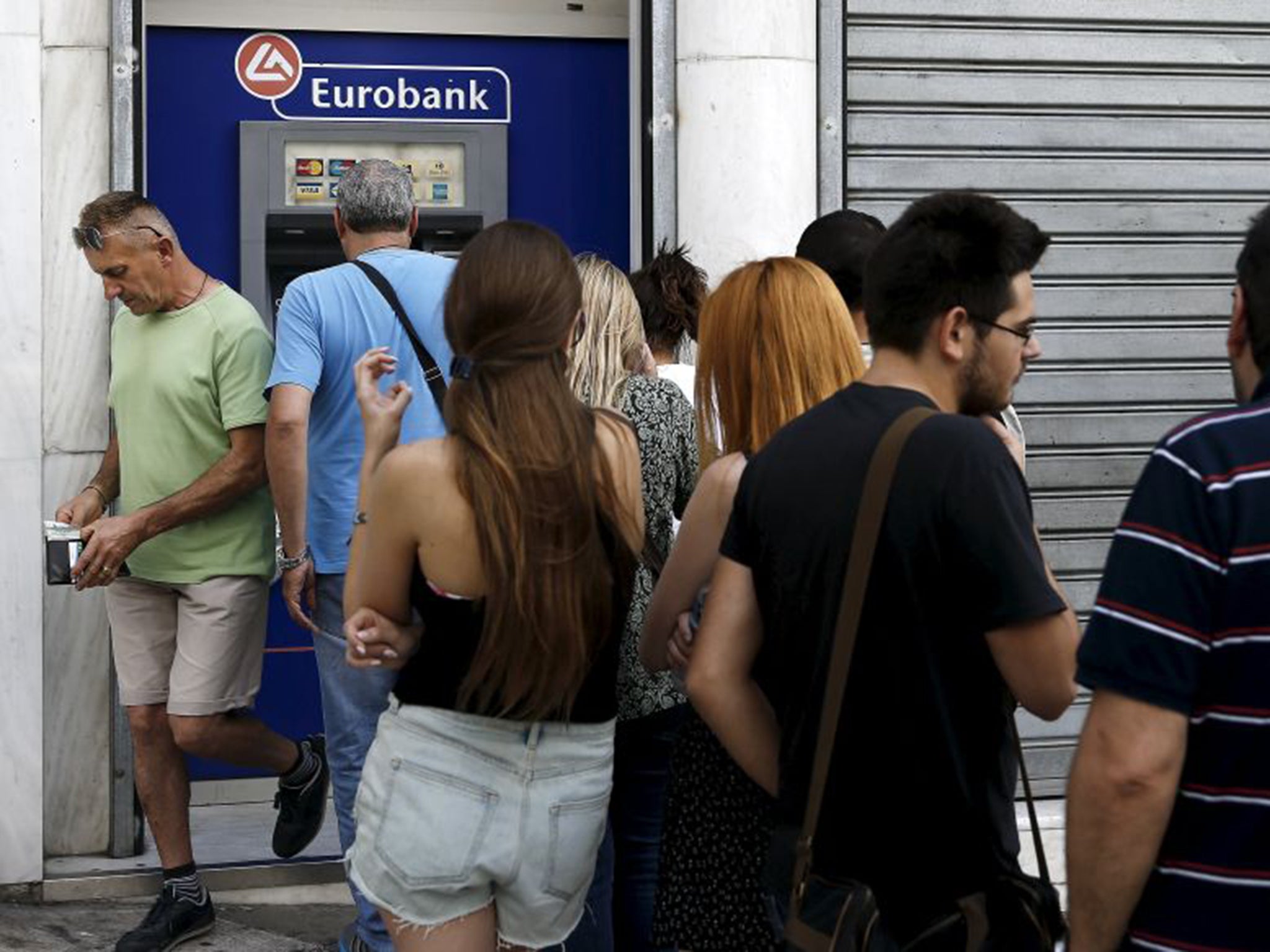 People queuing to use ATMs outside a bank in central Athens yesterday, unsure if capital controls were coming