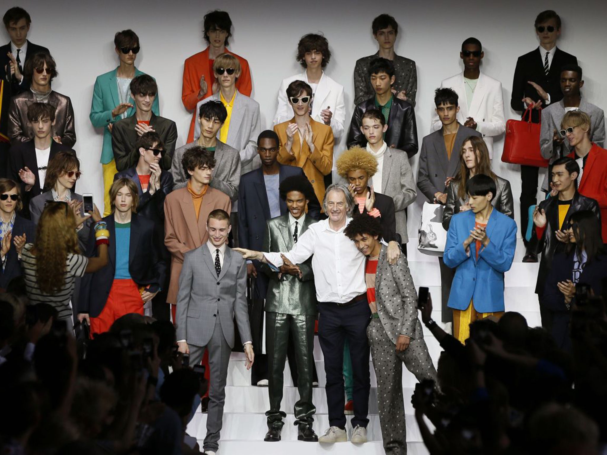 Paul Smith appearing on stage with his models at the end of his show. For spring, his designs were plain and simple