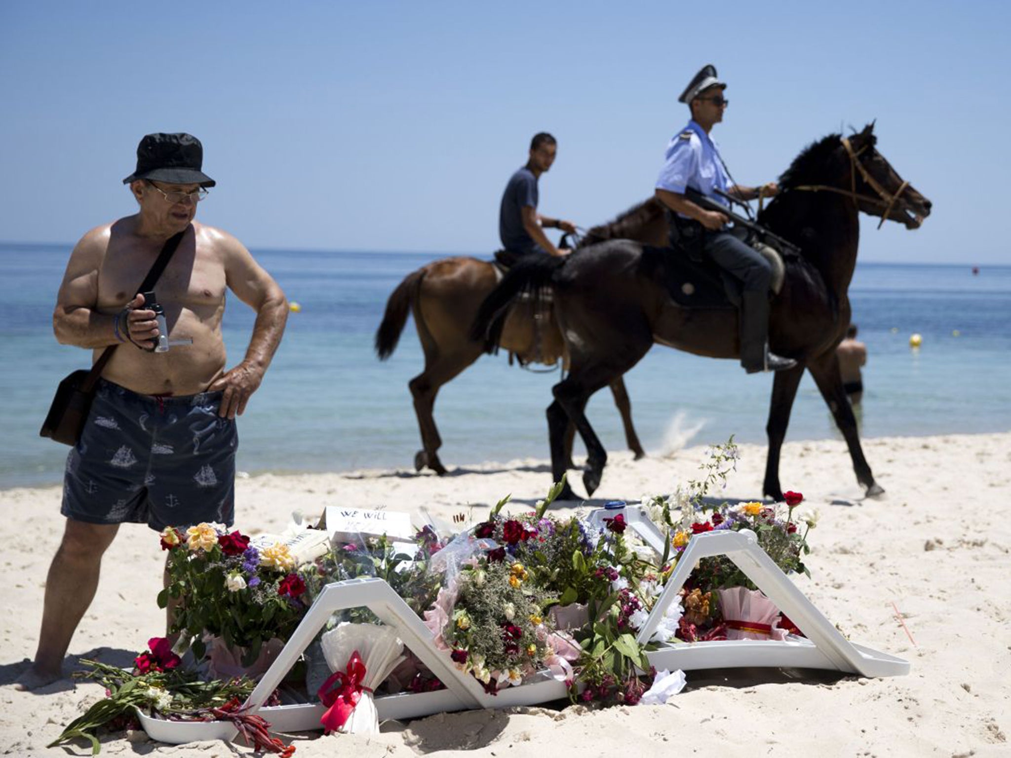 Policemen patrolling the beach in front of the Riu Imperial Marhaba Hotel in Sousse where tributes have been laid to the dead