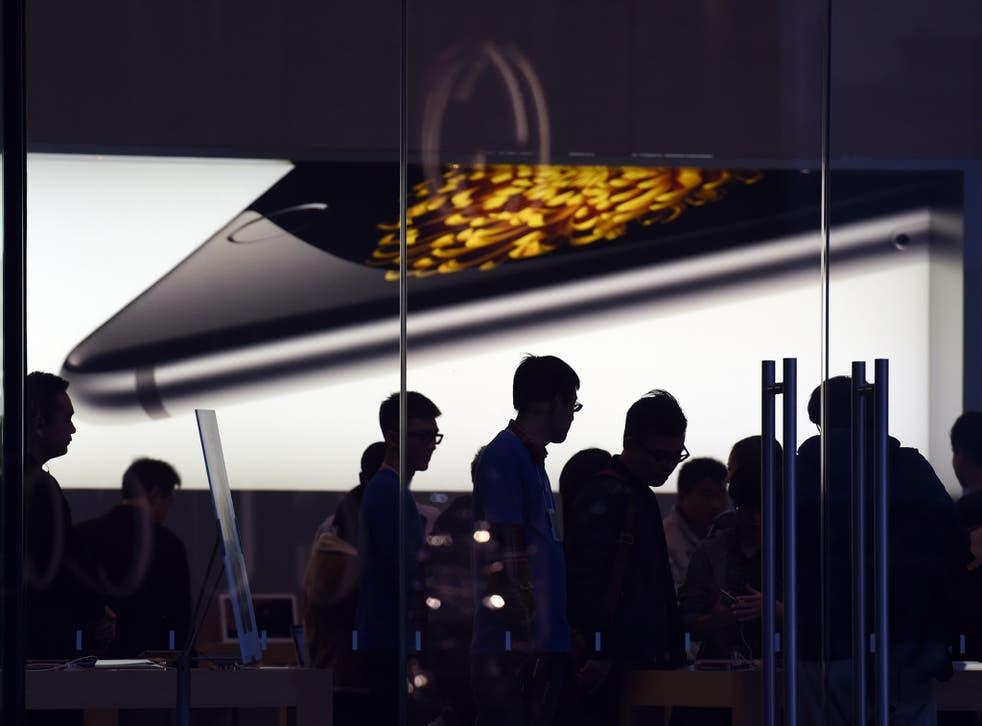Store attendants help customers at an Apple store selling the iPhone 6 in Beijing on October 23, 2014
