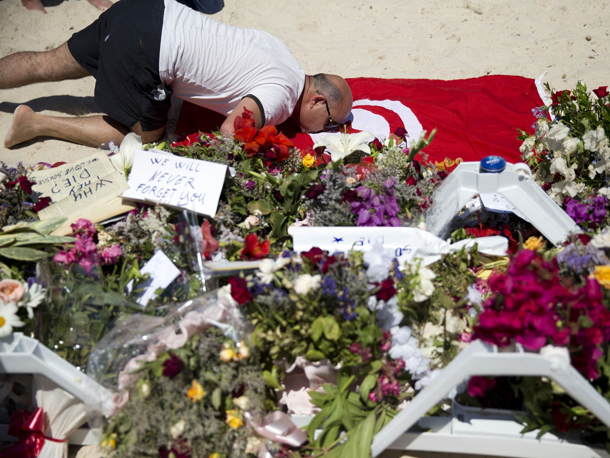 A man kisses a Tunisian flag at the site of a shooting attack on the beach in front of the Riu Imperial Marhaba Hotel in Port el Kantaoui