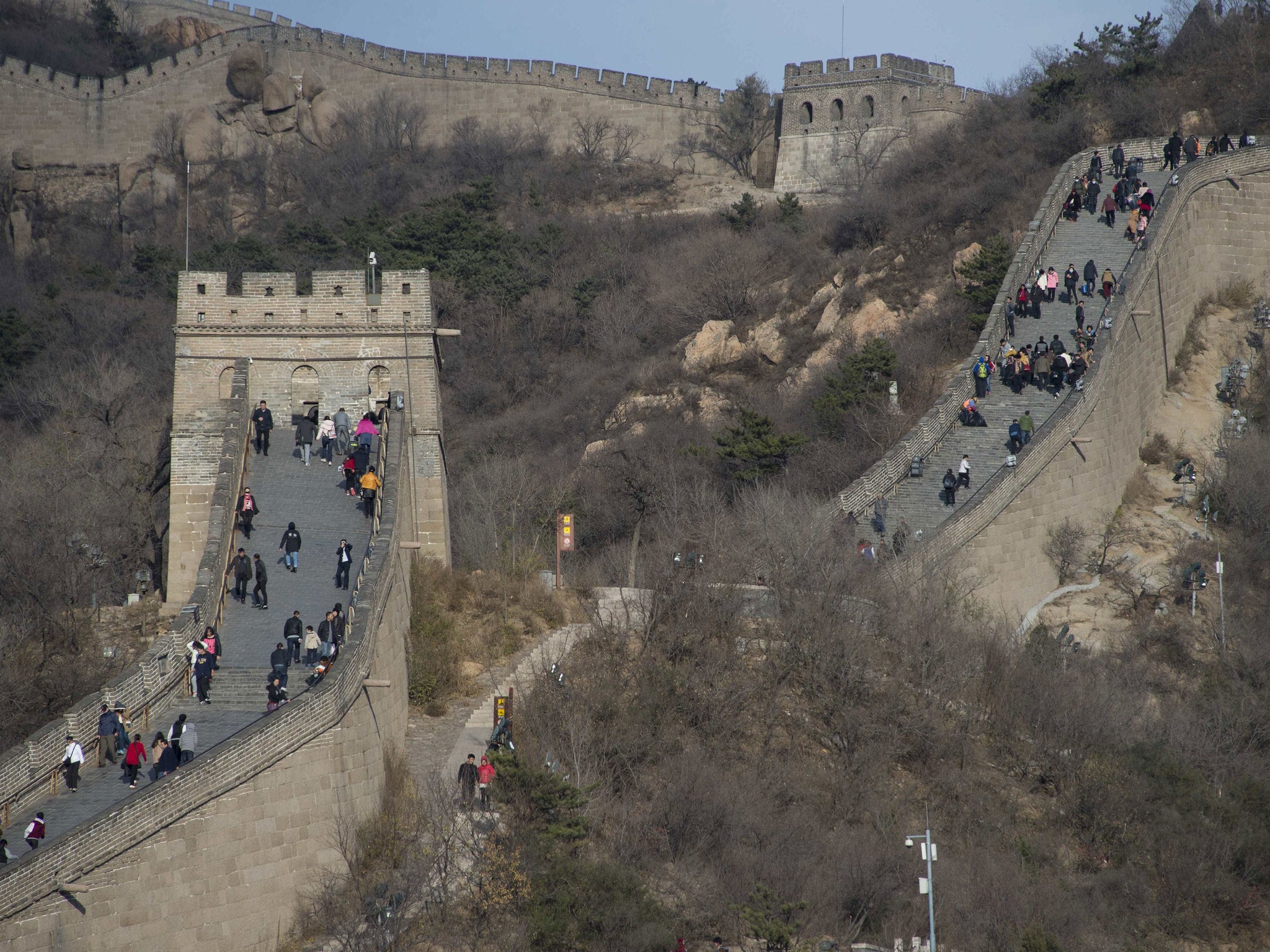 File: People walk along a section of the Great Wall of China at Badaling, north of Beijing, on November 11, 2014