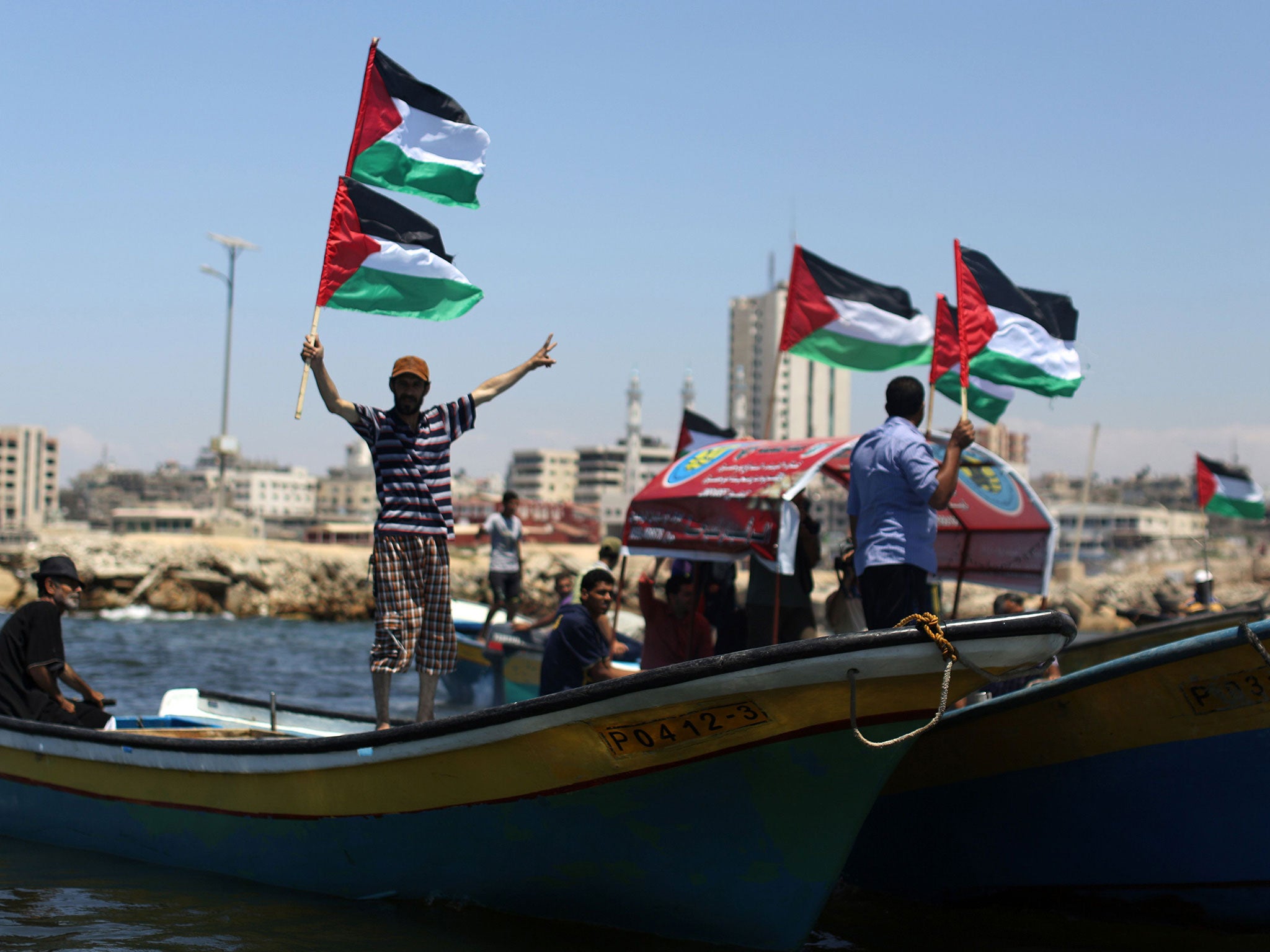 Palestinians wave their national flag as they ride boats during a rally in support of activists aboard a Pro-Gaza flotilla made up of four boats aimed at defying Israel's blockade of Gaza, at the seaport of Gaza City