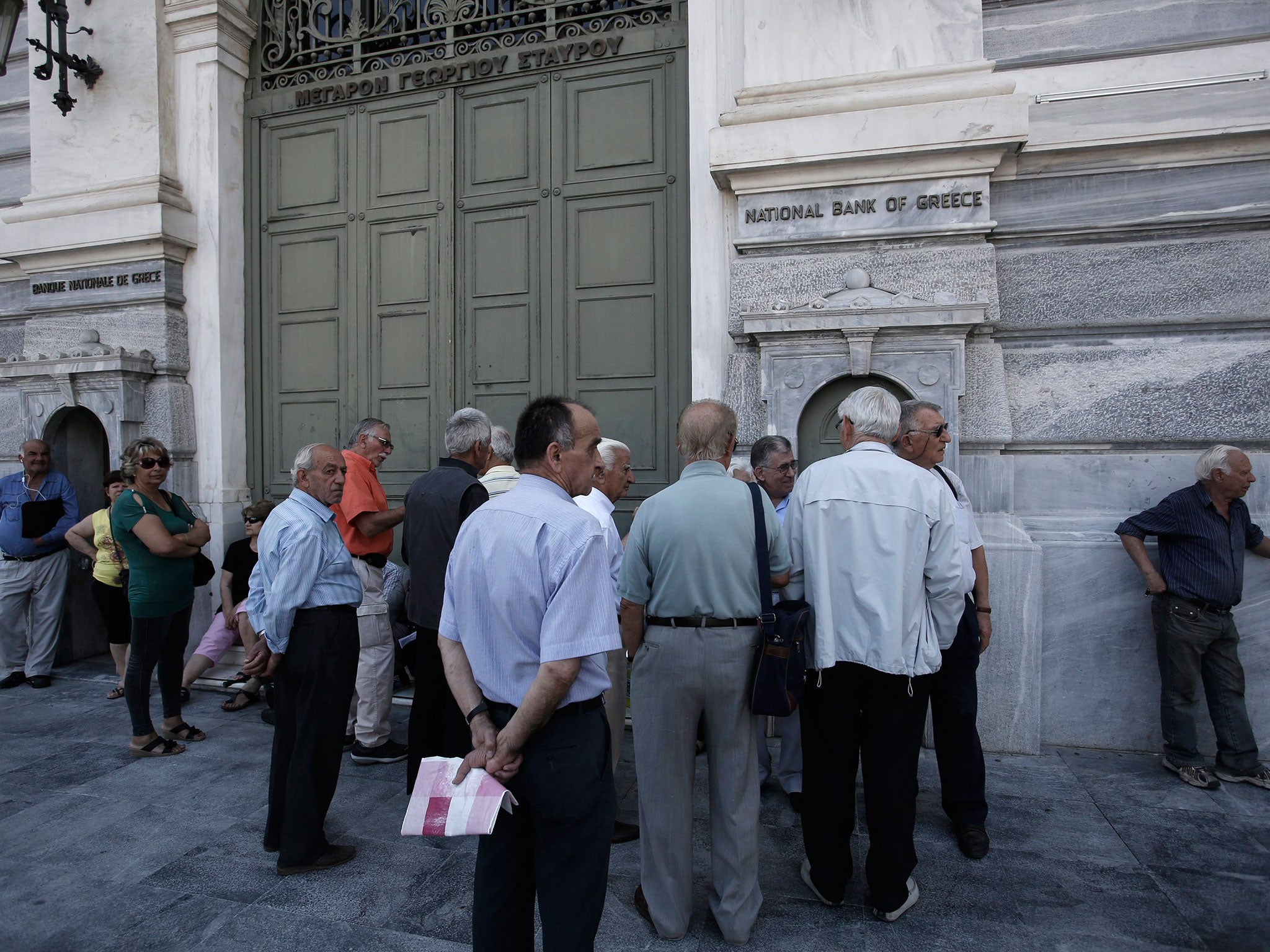 Customers wait outside a closed branch of the National Bank of Greece in Athens