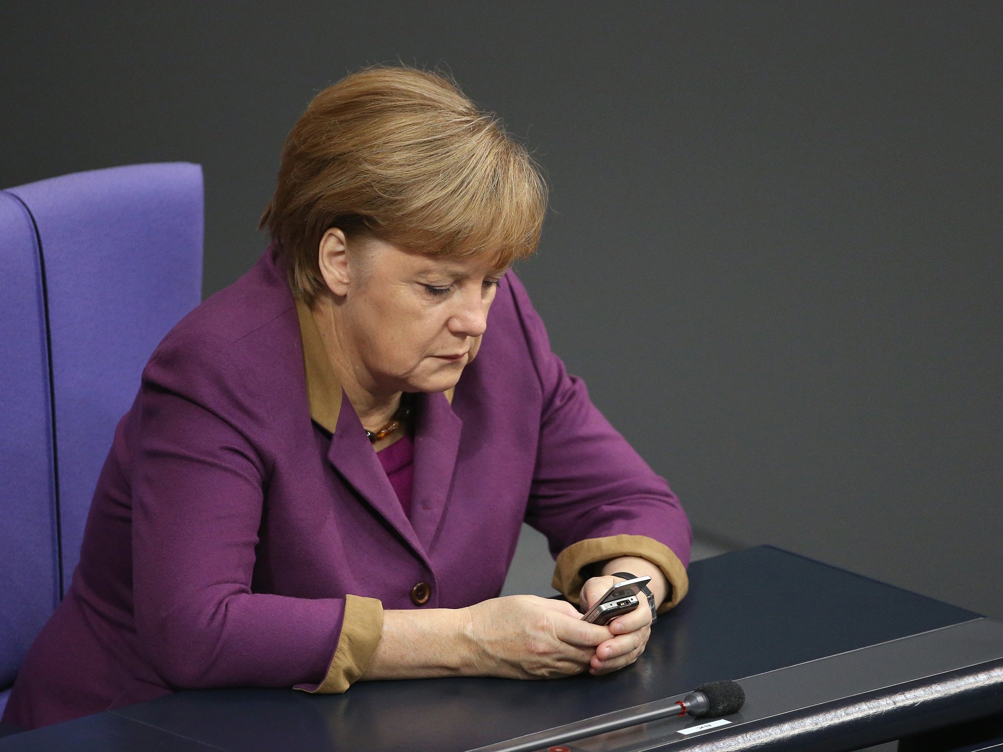 German Chancellor Angela Merkel checks her mobile phone during a session of the Bundestag on November 30, 2012 in Berlin