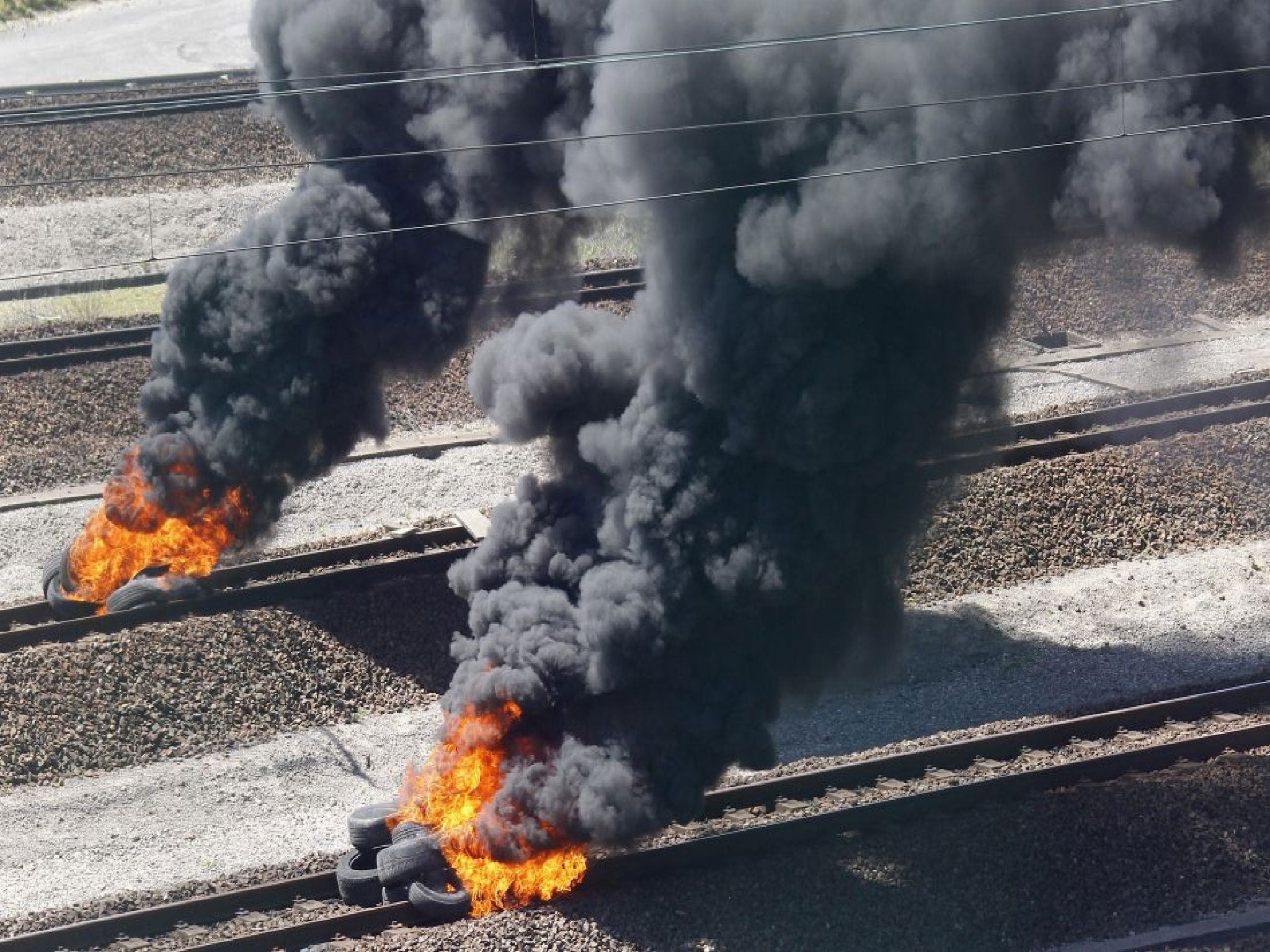 Striking workers invade the Eurotunnel train tracks in Calais, northern France, and burn tires in a protest against job cuts, Tuesday, June 30, 2015. About 100 striking French ferry workers have blocked train traffic between France and England for a seco