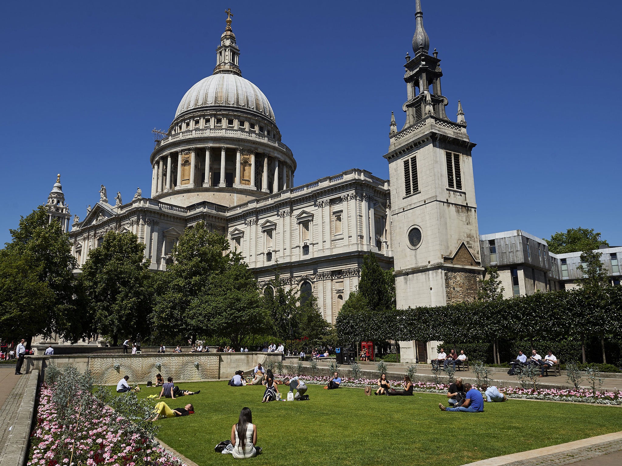 People enjoy the sunshine in front of St Paul's Cathedral in central London