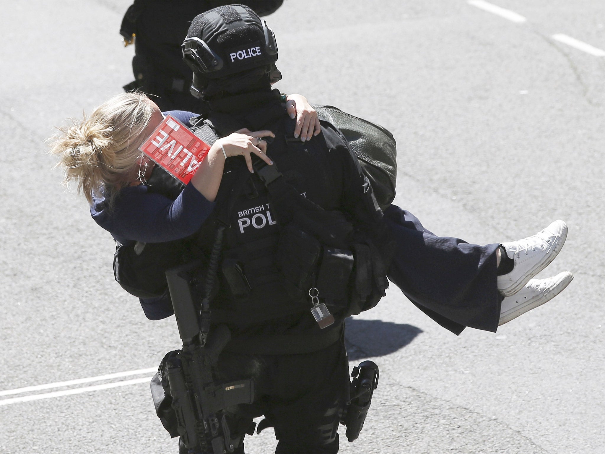 A police officer carries a casualty to safety