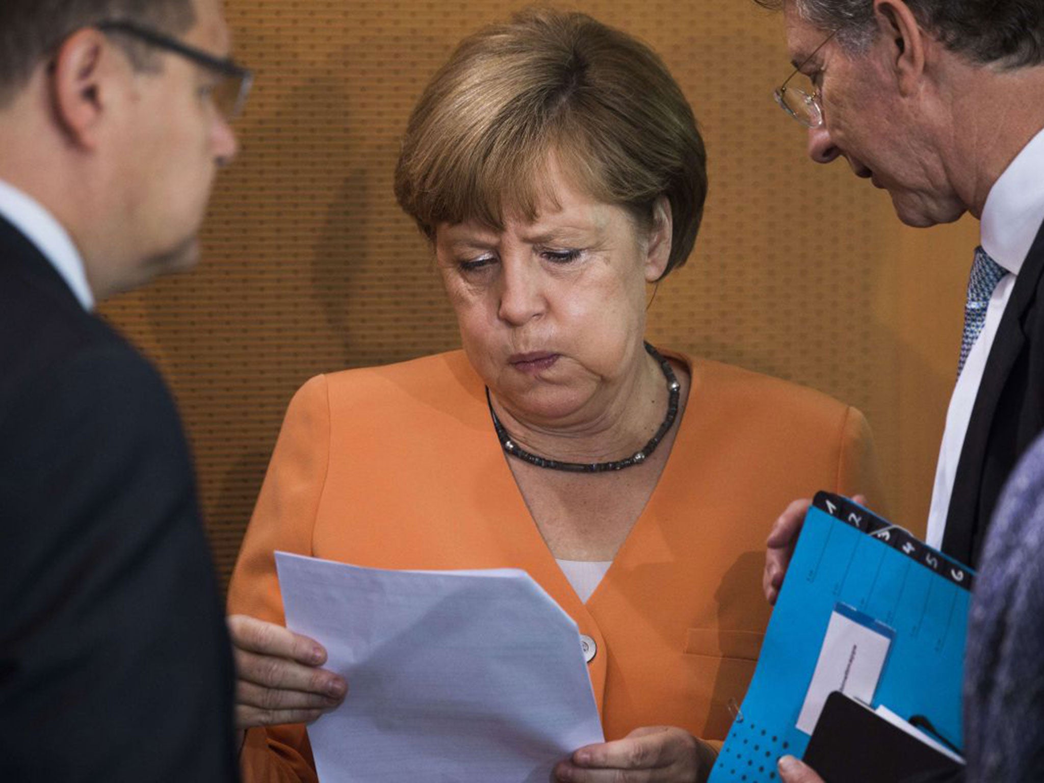 German Chancellor Angela Merkel (C) reacts as she is given a note as she arrives for the weekly cabinet meeting at the Chancellery in Berlin on July 1, 2015.
