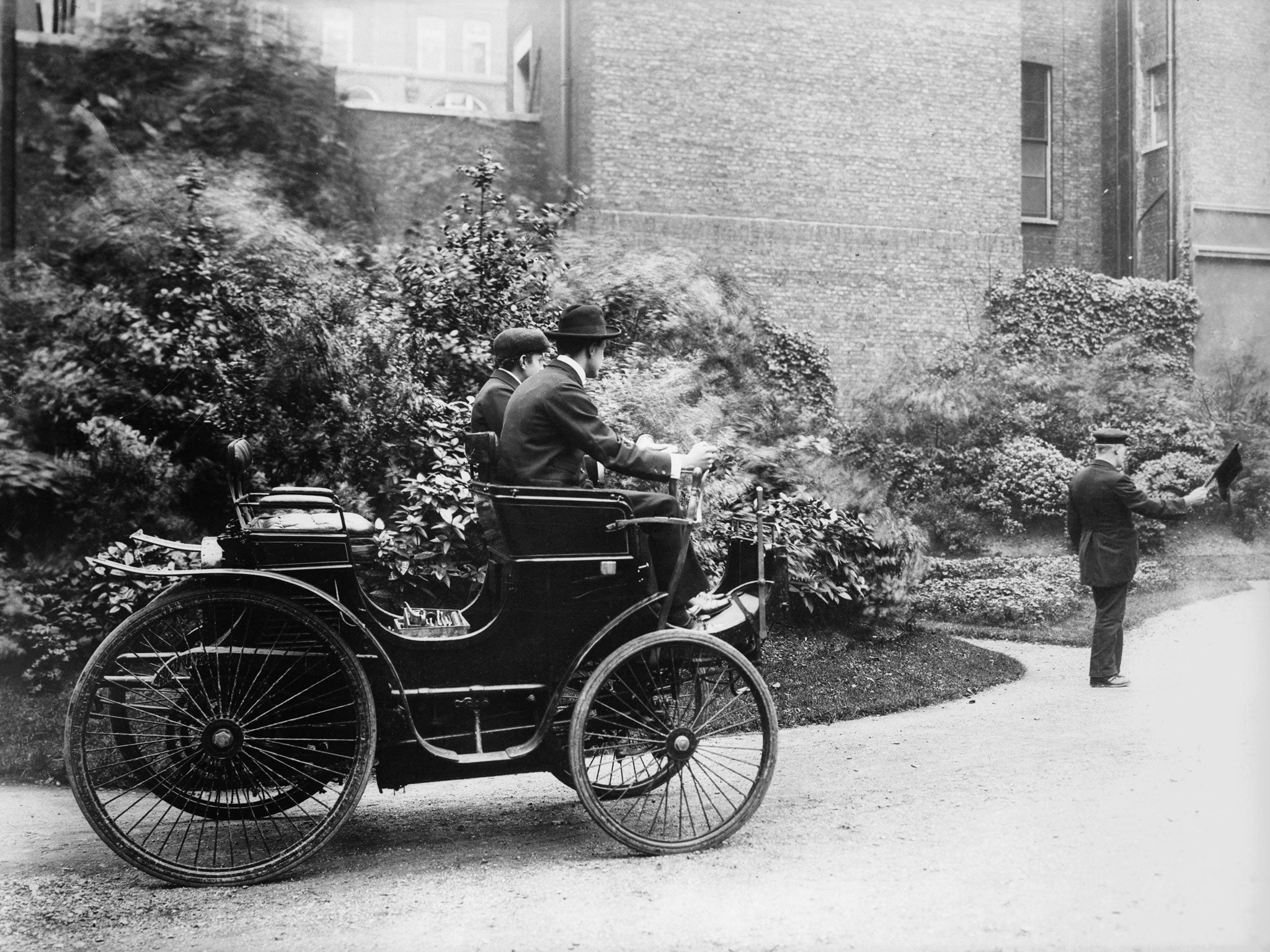 English motor car manufacturer Charles Stewart Rolls in his first car imported from France, with a man walking in front with a red flag, as the law of the time required
