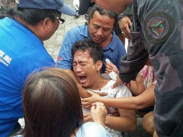 A survivor of a passenger ferry that capsized in rough waters cries after arriving at the pier in Ormoc City