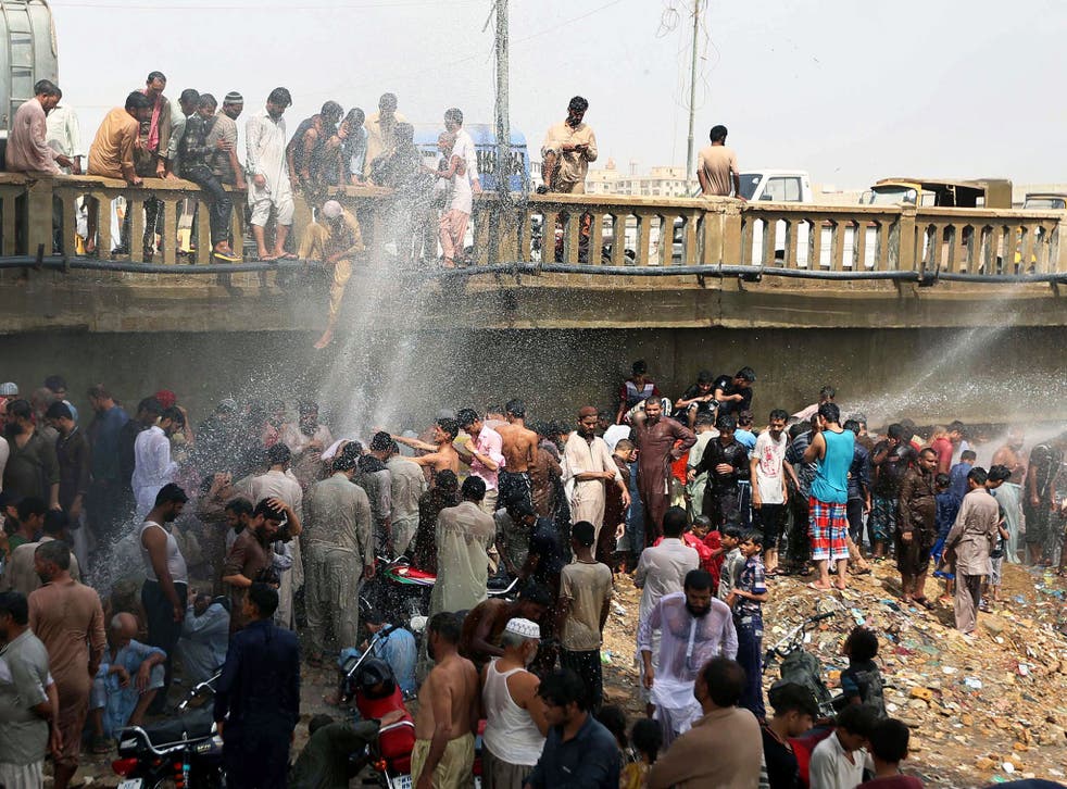 People attempt to cool off near a damaged water pipe in Karachi