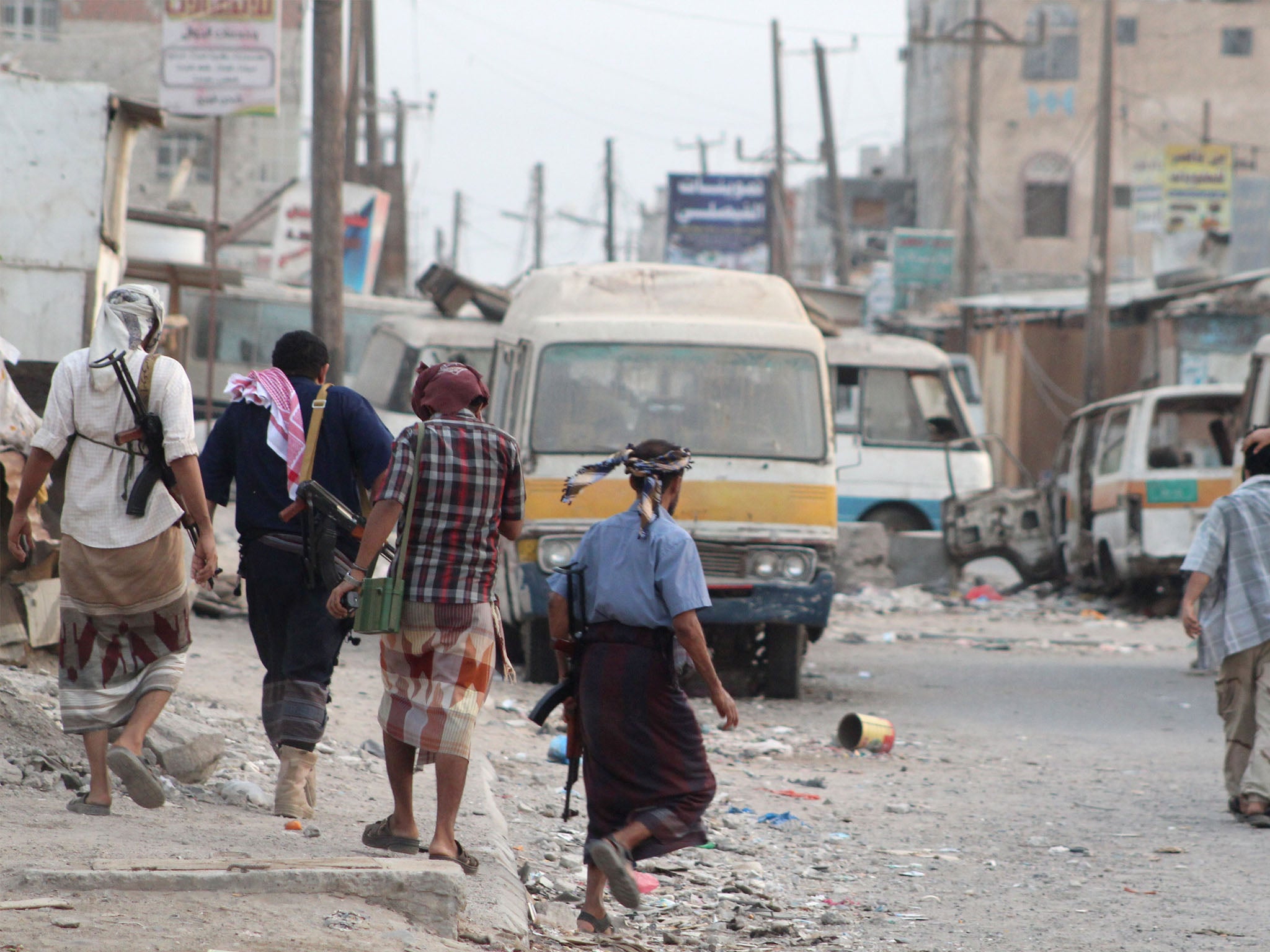 Yemeni fighters loyal to exiled President Abedrabbo Mansour Hadi walk on a damaged street in the Dar Saad suburb of the southern city of Aden on 2 July 2015.