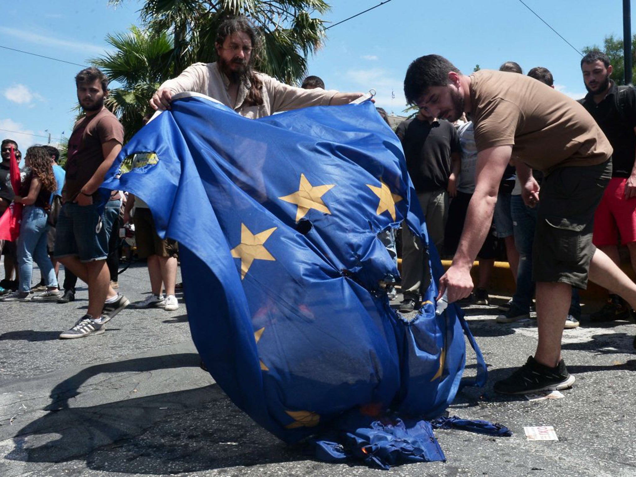 Leftist protesters try to burn an EU flag at European Commission offices in Athens on Thursday