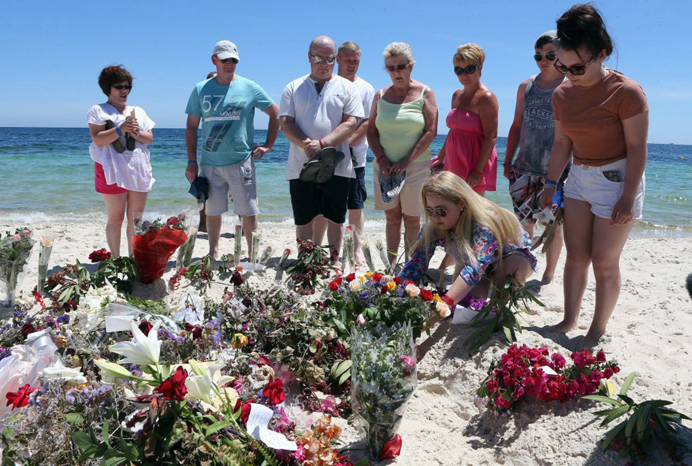 Tourists place flowers in tribute to the people killed in the terror attack in Sousse, in which 38 people lost their lives