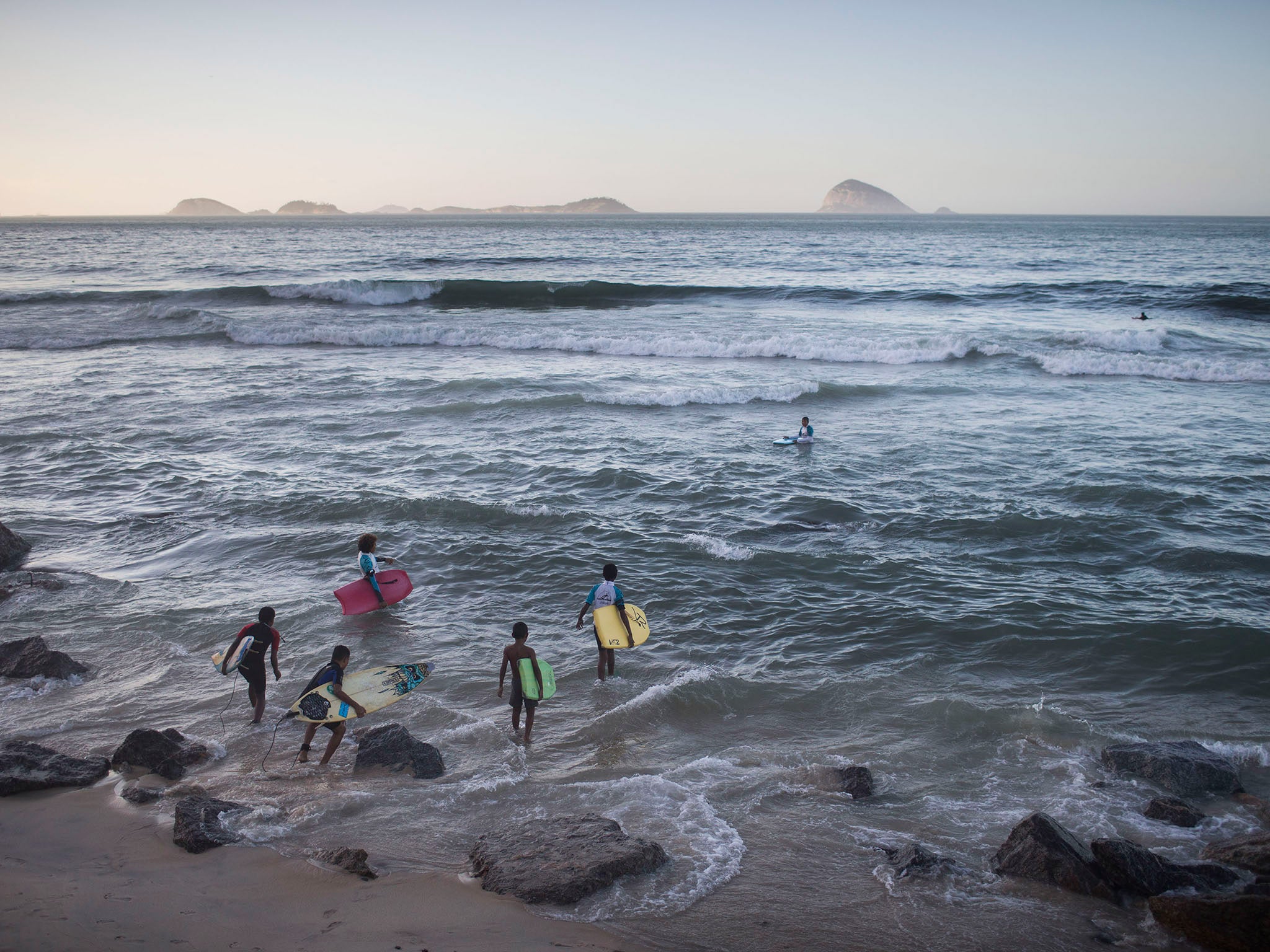 Young surfers from the Rocinha slum enter the water at Sao Conrado beach in Rio de Janeiro, Brazil. Everyday barefoot boys hustle down the inclined alleyways of the Rio de Janeiro slums they call home, surf boards under their arms. They head to nearby Sao