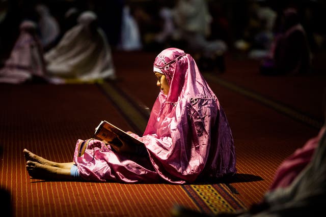 A Indonesian woman reads the Koran on the first day of Ramadan 