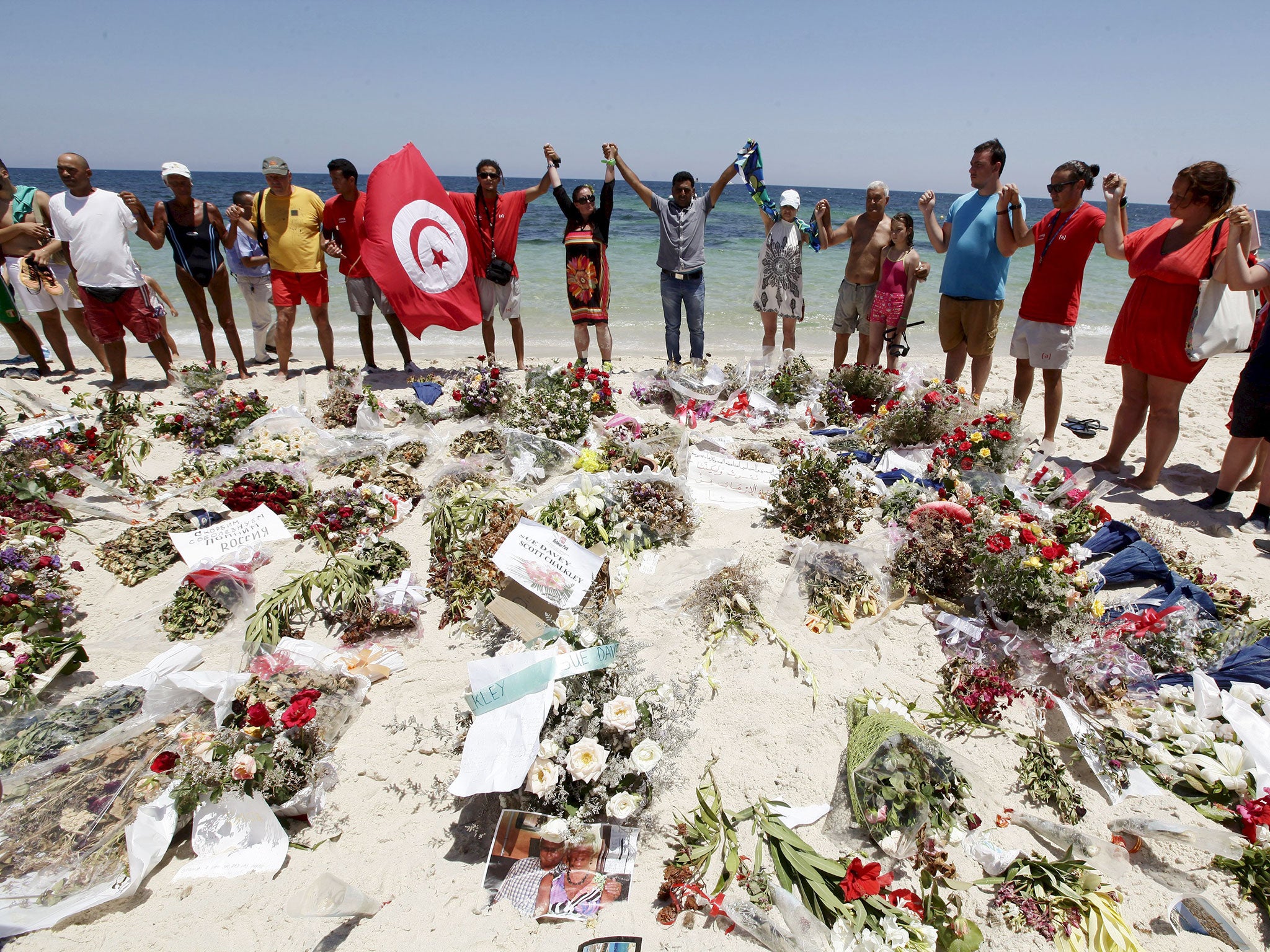 People join hands as they observe a minute's silence in memory of those killed in a recent attack by an Islamist gunman, at a beach in Sousse, Tunisia