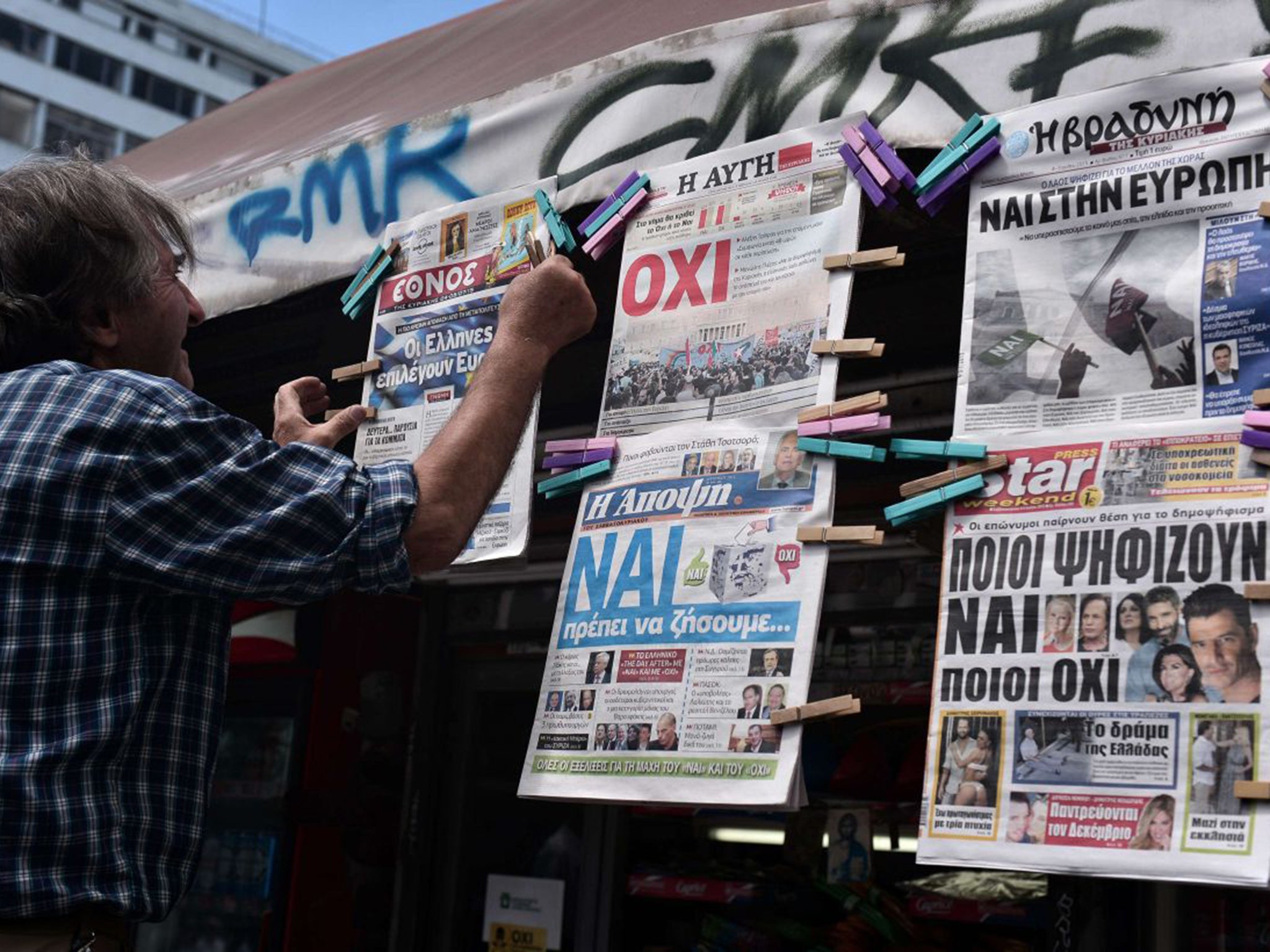 Yes and No… Newspapers with opposing headlines are put up in Athens
