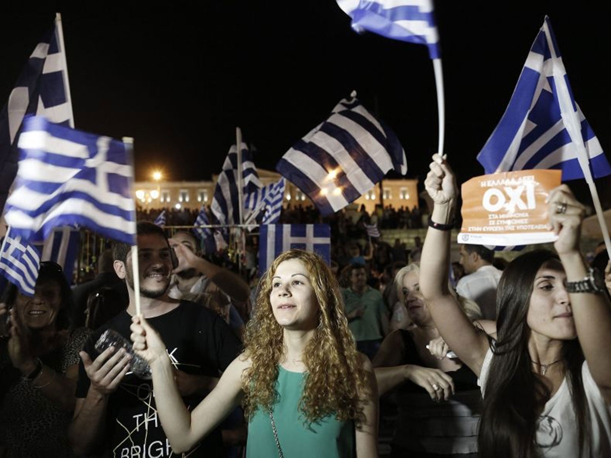 Supporters of the 'No' campaign wave flags and react after the first results of the referendum at Syntagma Square, in Athens