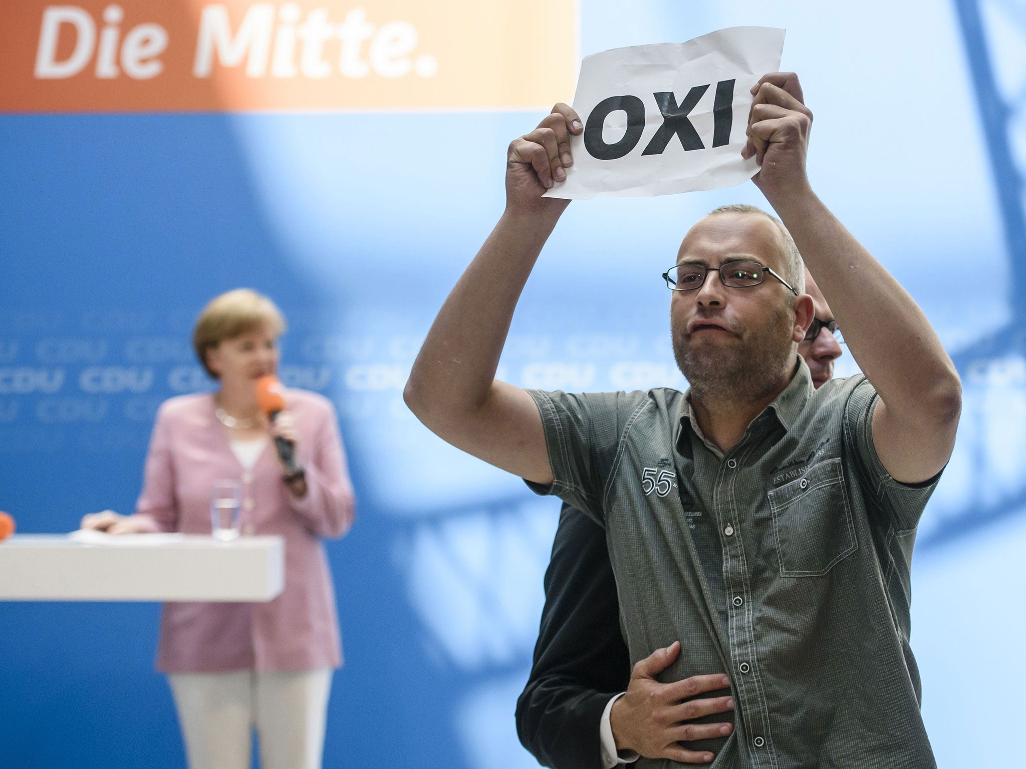 A protester holds a sheet with the Greek word for 'No' during an open house presentation of Germany's conservative Christian Democratic Union (CDU) party at Konrad Adenauer House