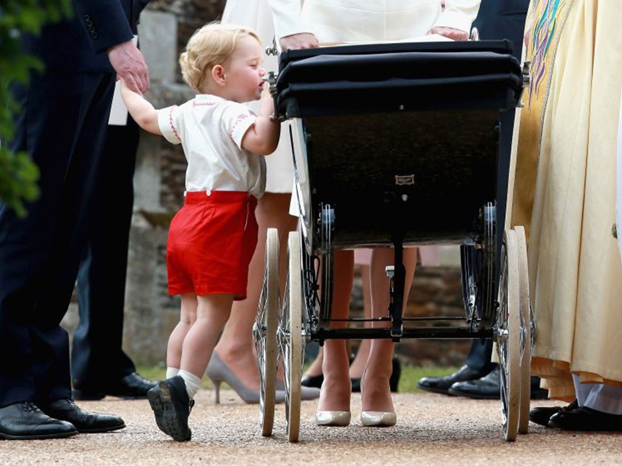 Prince George of Cambridge looks into the pram carrying his sister Princess Charlotte