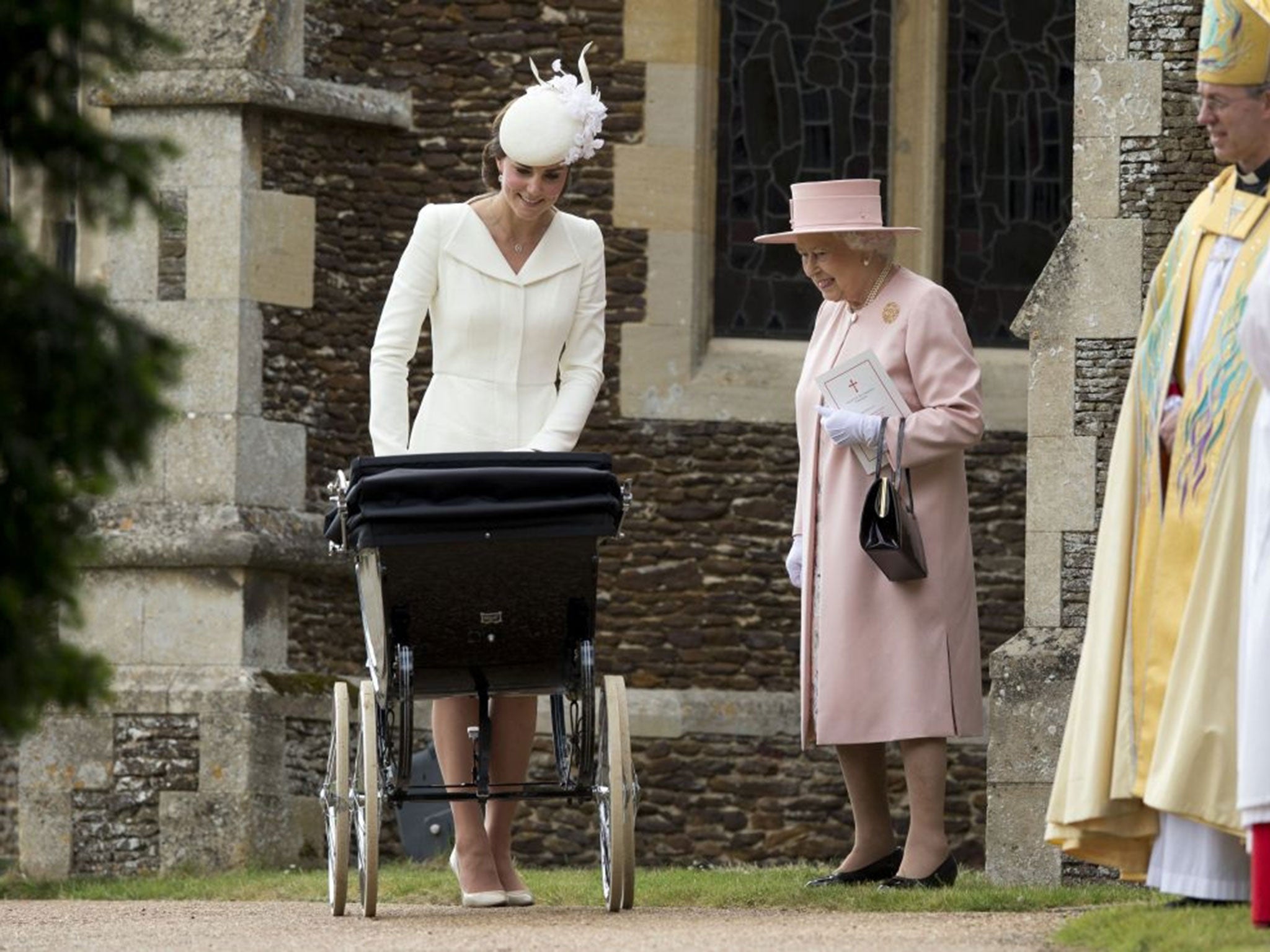 Britain's Queen Elizabeth II stands with Kate the Duchess of Cambridge whilst pushing Princess Charlotte in a pram as they leave after attending the Christening of Britain's Princess Charlotte at St. Mary Magdalene Church in Sandringham, 2015